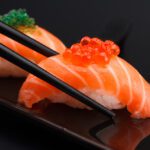 Salmon,Sushi,Nigiri,In,Chopsticks,Over,Black,Background